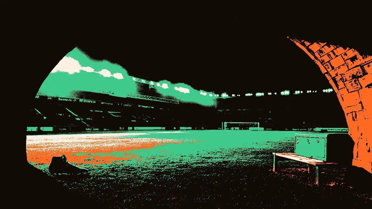Un tunnel de stade vide illuminé par des projecteurs, avec un banc en bois fermé et une seule chaussure posée sur l'herbe à côté d'une armoire métallique au bord du terrain, évoquant une sélection d'effectif.
